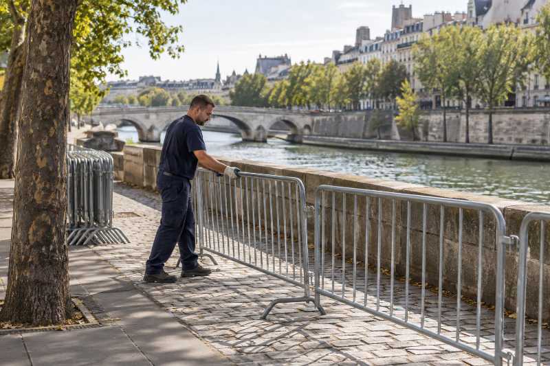Déménageur posant des barrières métalliques sur un quai au bord d'un fleuve