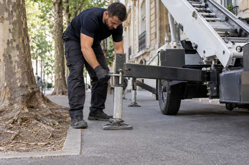 Stabilisation des vérins d'un monte-meuble sur un trottoir étroit bordé d'arbres