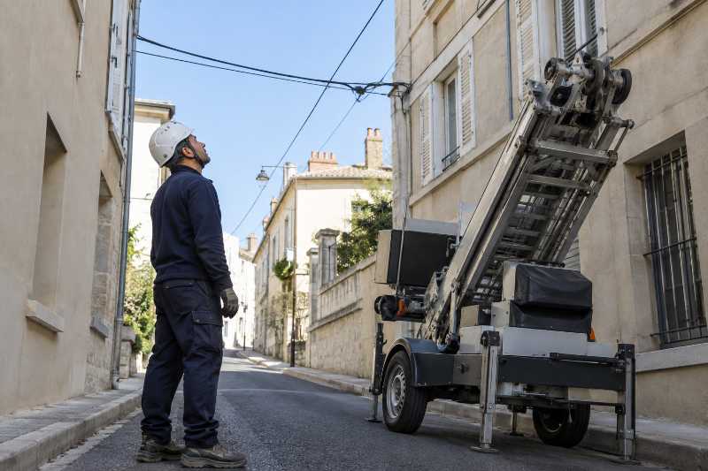 Opérateur vérifiant la position de câbles aériens avant de déployer un monte-meuble