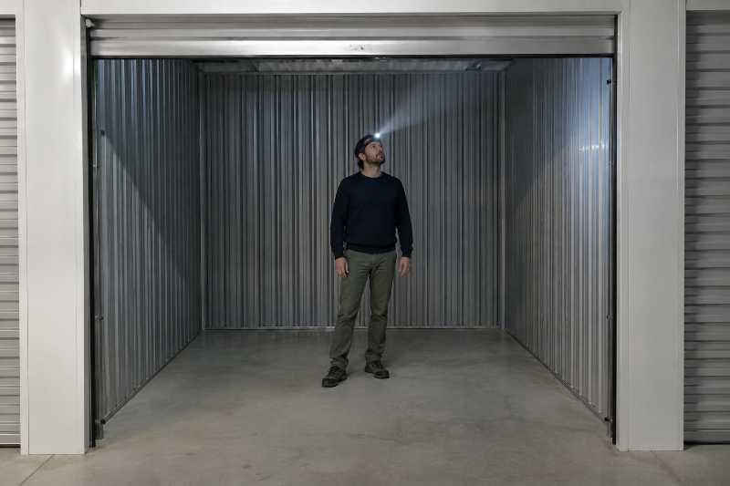 Client visitant un box de stockage libre accès, lampe frontale allumée